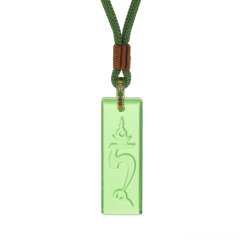 Flat lay view of Green Tara Tibetan protection necklace with braided green cord and decorative knot, rectangular crystal glass pendant