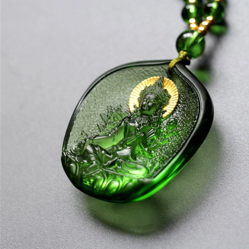 Side view of translucent dark green Liuli pendant showing embossed Buddha relief with gold halo