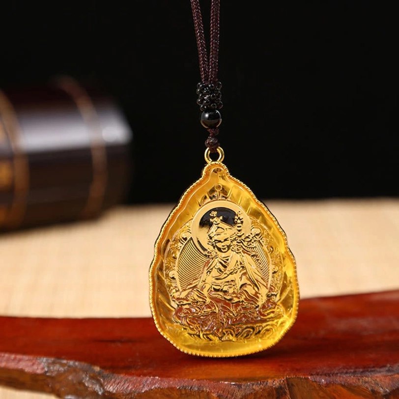 Golden amber Tibetan Guru Buddha crystal pendant with intricate engraving, gold rim, and black beaded necklace