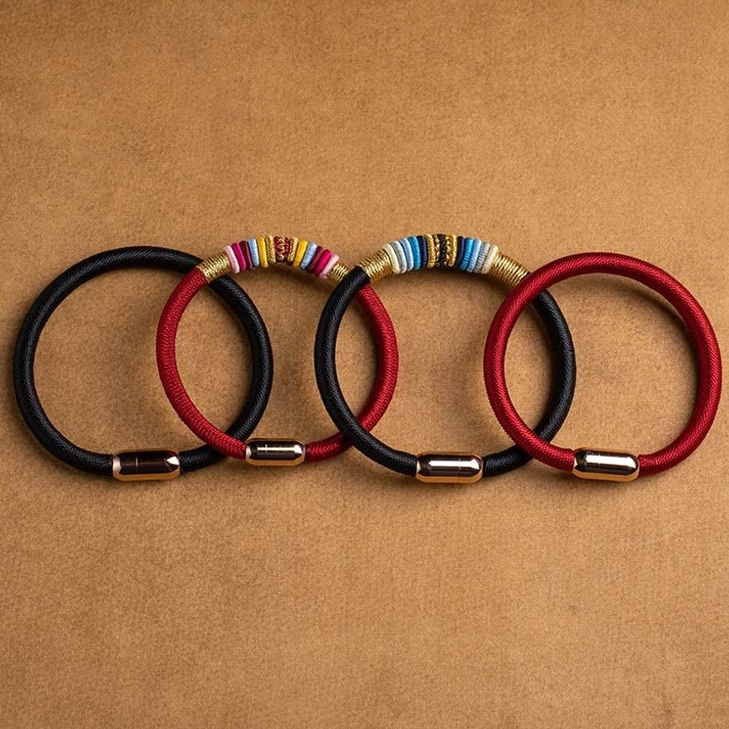 Multiple Tibetan Vajra Knot magnetic bracelets in red and black styles, overhead arrangement on kraft paper