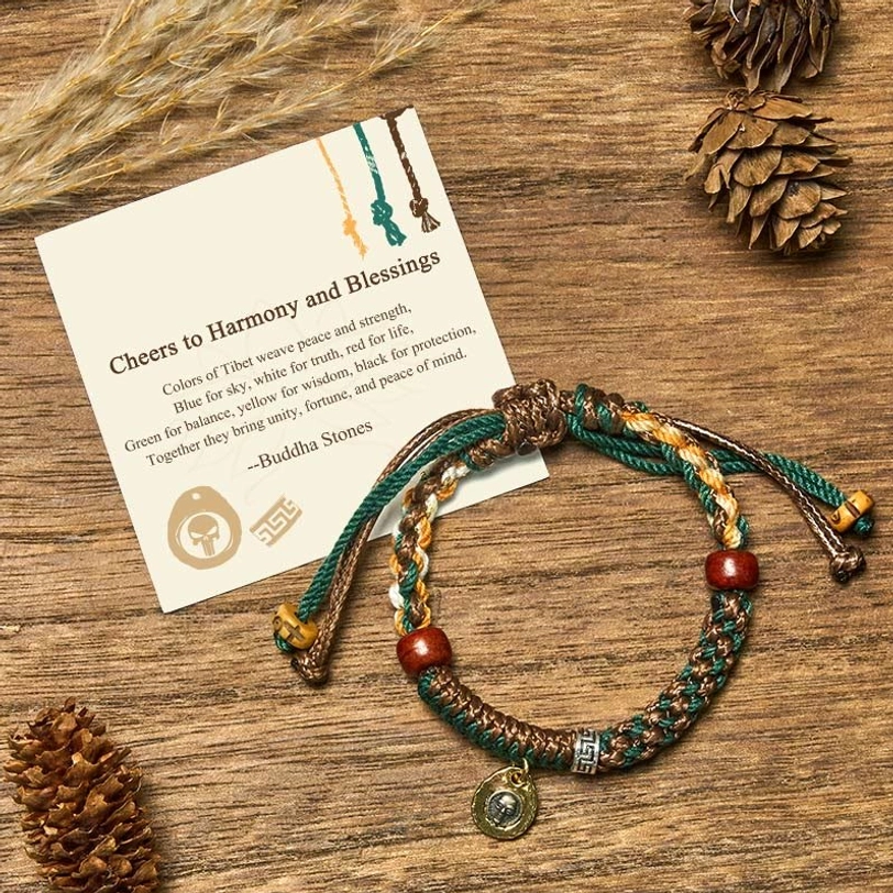 Tibetan harmony rope bracelet flat lay with multicolor braided cord, wooden beads, and metal charm on rustic wooden table with pinecones