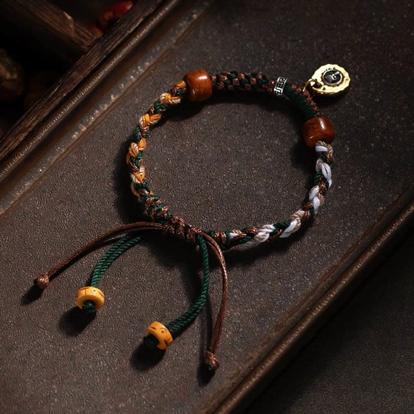Tibetan woven rope bracelet with multicolor braided cord and brown wooden beads on dark wooden surface background