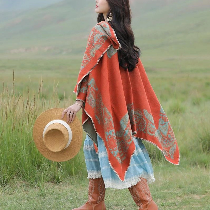 Hooded Tibetan poncho wrap with light stitched border positioned over shoulder, grassland outdoor setting