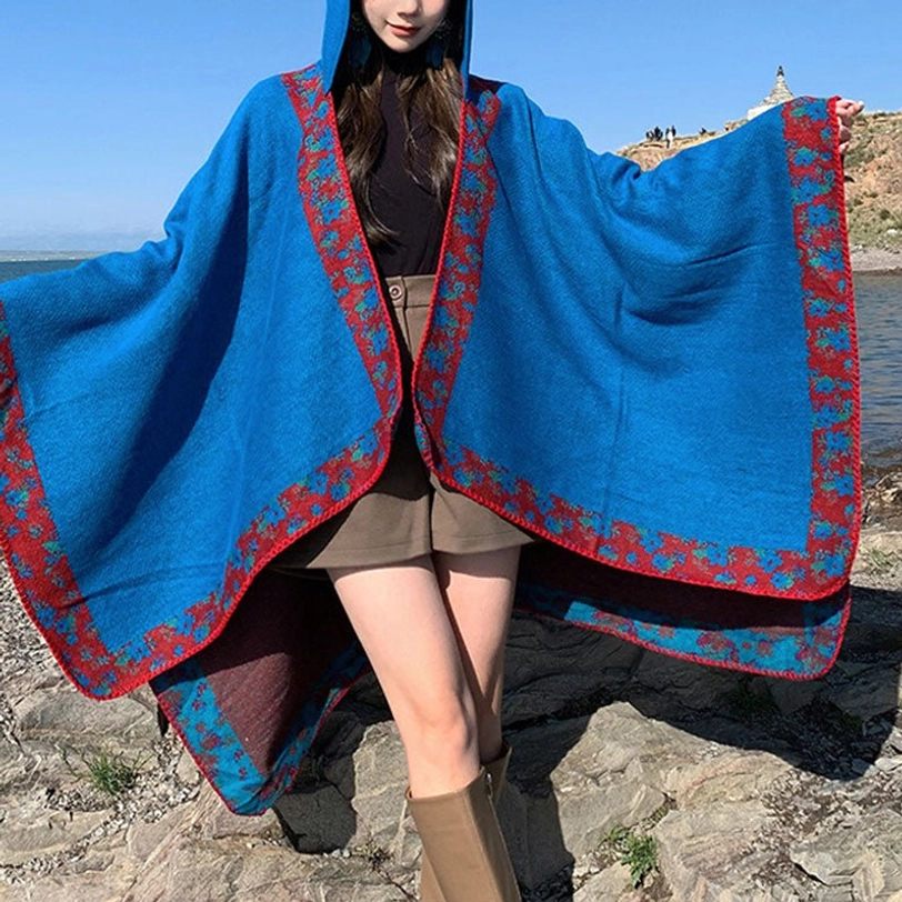 Blue Tibetan hooded wrap shawl front three-quarter view with floral trim on grassland mountain setting