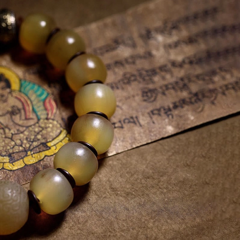 Tibetan sheep horn bracelet partial view showing translucent yellow barrel beads on Buddhist tapestry