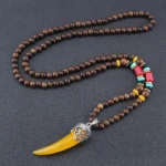 Yellow resin horn pendant necklace with wenge wood beads and turquoise accents - Tibetan inspired protection amulet flat lay