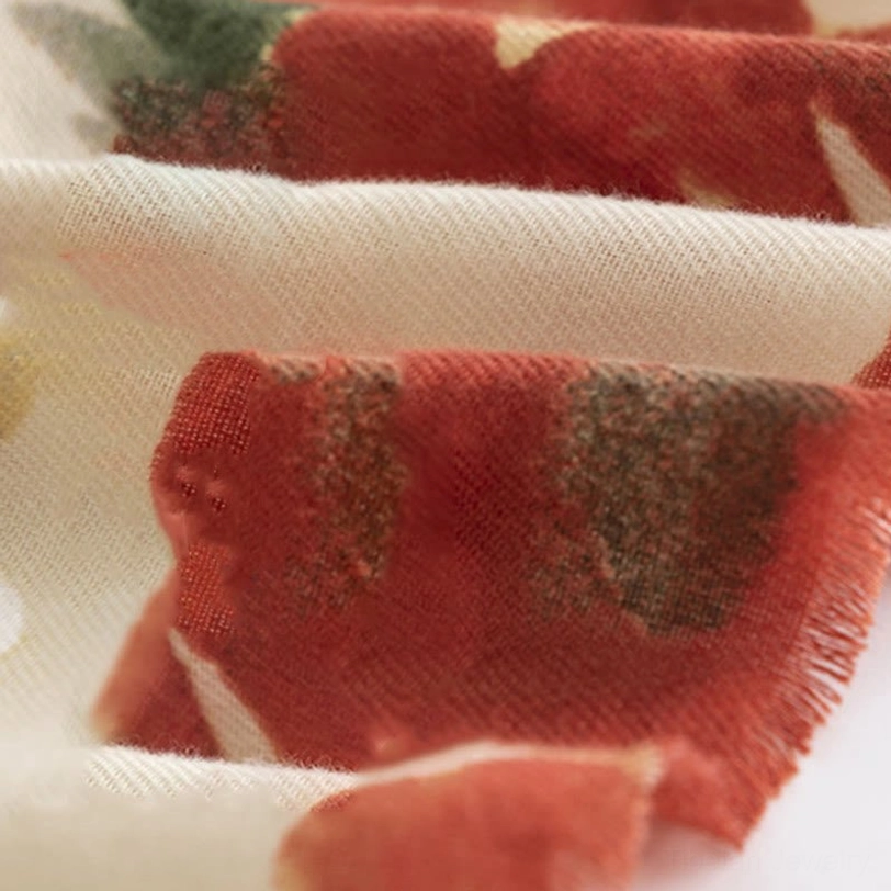 Close-up of Tibetan scarf fabric showing rust red and cream tones with soft cozy woven texture and raw frayed edges