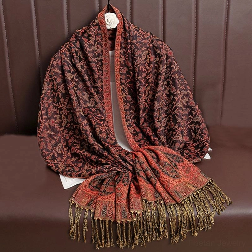 Dark brown and terracotta orange Tibetan jacquard tassel shawl with paisley weave pattern, displayed on sofa backrest with long decorative fringe hem