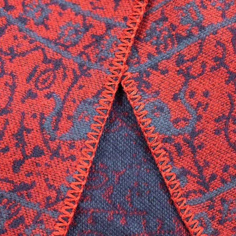 Close-up macro view of Tibetan elephant jacquard fabric showing red and dark grey woven motifs with contrast stitching