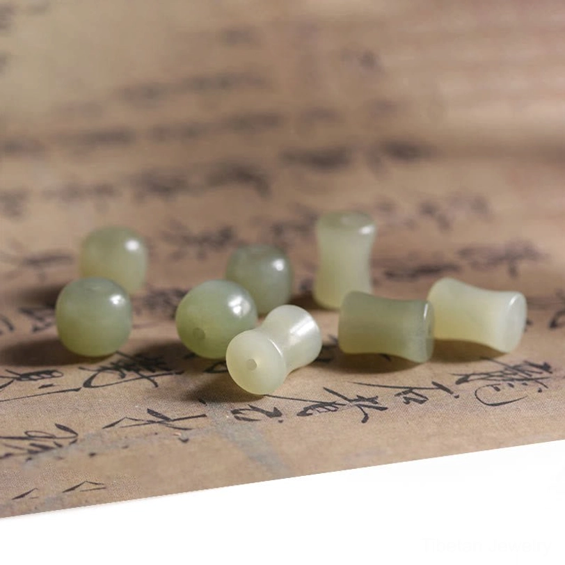 Loose Hetian jade beads with bamboo-joint carving scattered on traditional Chinese paper background