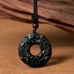 Tibetan black-green jade Pixiu peace buckle pendant necklace with intricate carved details on wooden background