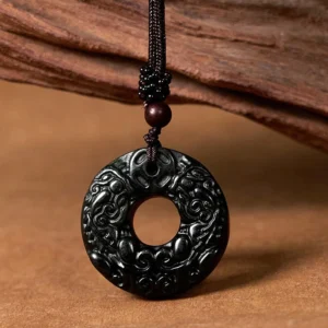 Tibetan black-green jade Pixiu peace buckle pendant necklace with intricate carved details on wooden background
