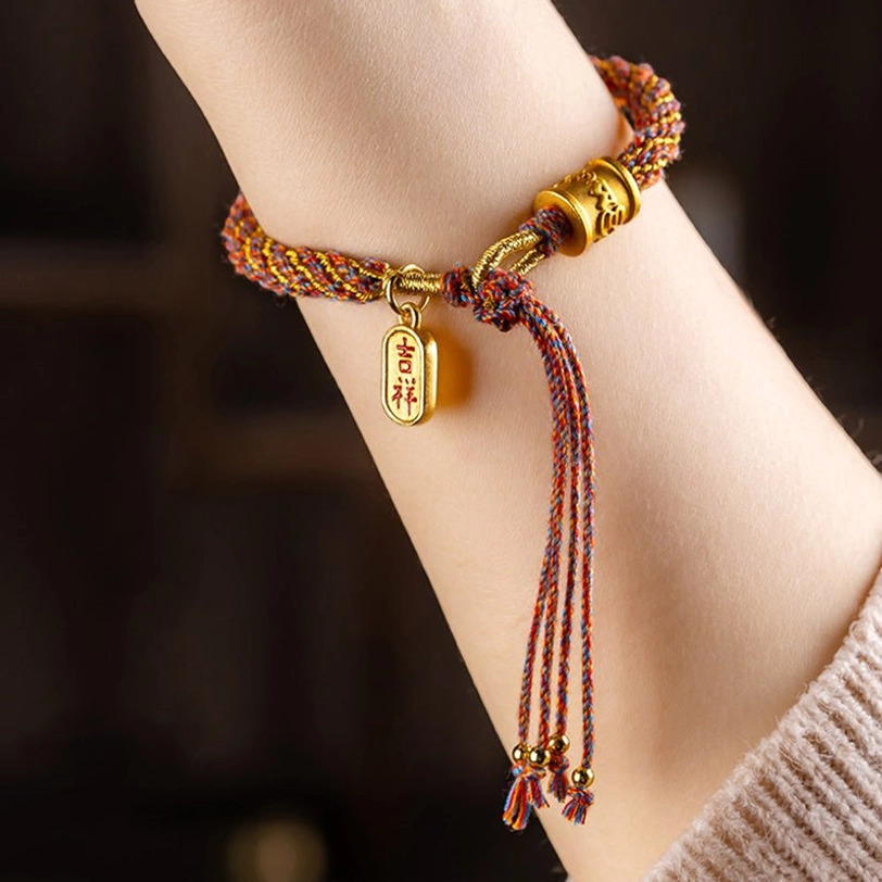 Closeup of Tibetan braided bracelet with multicolor rope and Jixiang pendant on wrist