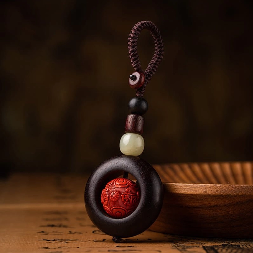 Tibetan protection keychain close-up showing red sandalwood ring and hand-carved cinnabar bead with mantra