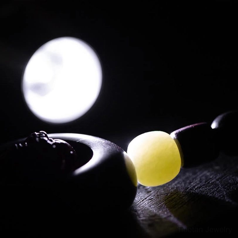 Minimalist shot of Tibetan keychain with jade accent bead and dark wood ring backlit detail