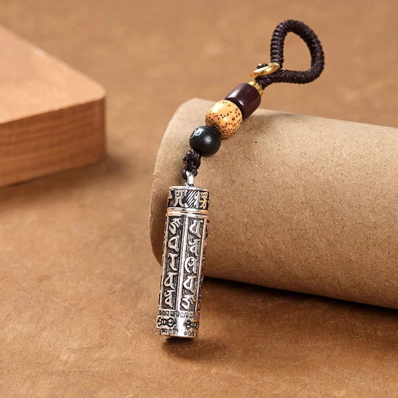 Tibetan Om Mani Padme Hum keychain three-quarter view with engraved copper tube, dark braided rope and mixed beads