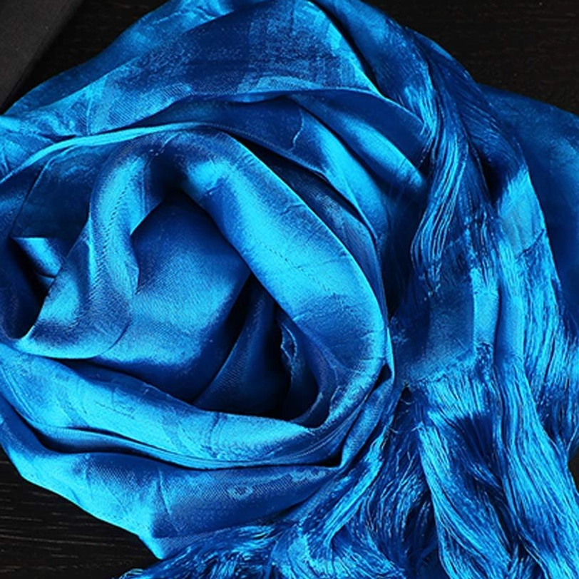 Blue tibetan khata scarf close-up showing coiled draped fabric and subtle woven jacquard pattern detail