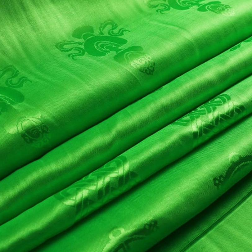 Close-up of Tibetan khata showing satin fabric weave and embossed auspicious Buddhist symbols and patterns