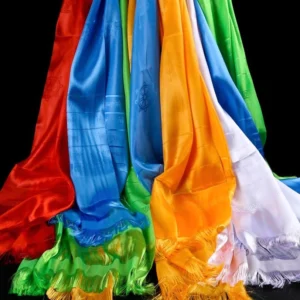 Tibetan five-color khata silk scarves hanging with visible tassels and embossed auspicious patterns on dark studio background