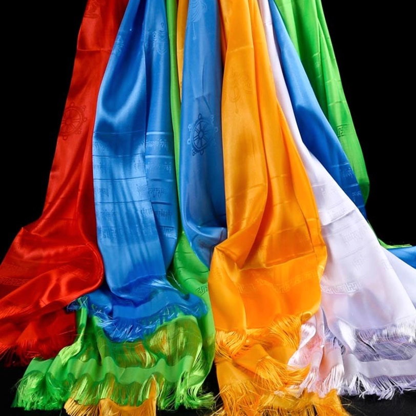 Tibetan five-color khata silk scarves hanging with visible tassels and embossed auspicious patterns on dark studio background