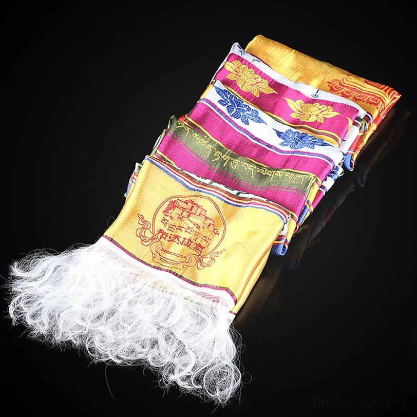 Folded tibetan multicolored khata showing fluffy white tassels, layered embroidered patterns, and stacked presentation