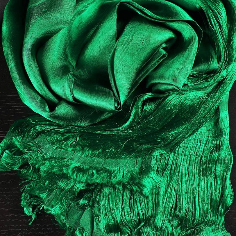 Close-up detail of green tibetan khata showing intricate jacquard weaving pattern and glossy silk texture