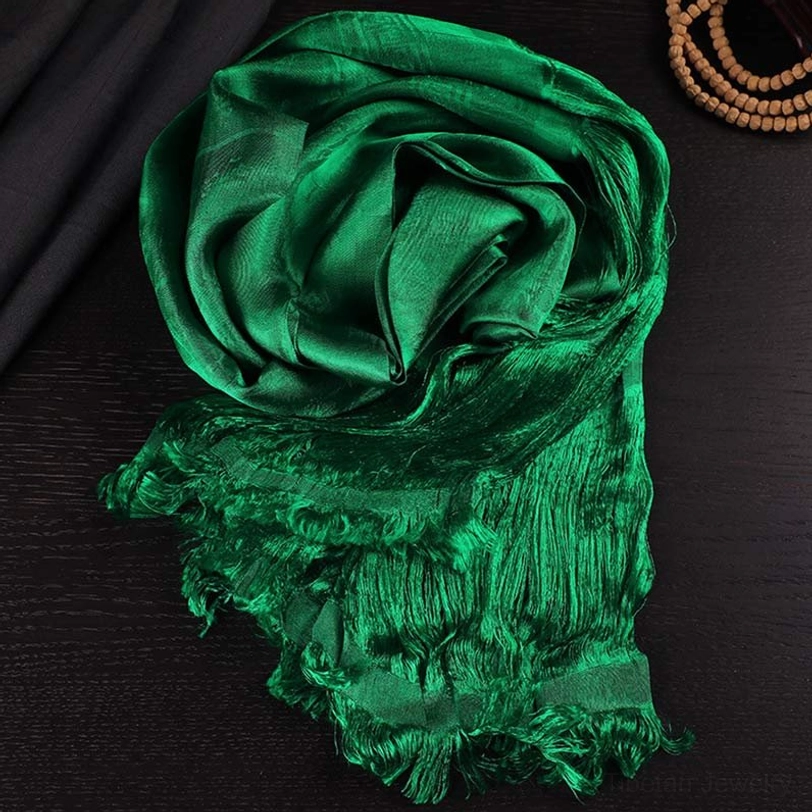 Tibetan green 5-color jacquard khata silk scarf with frayed tassels, overhead flat lay on dark wooden table