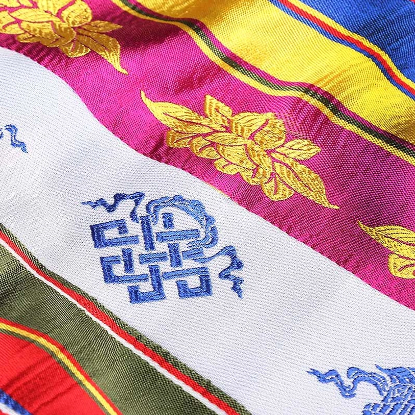 Tibetan khata scarf detail showing blue sacred patterns, golden floral embroidery, and multicolor striped weaving