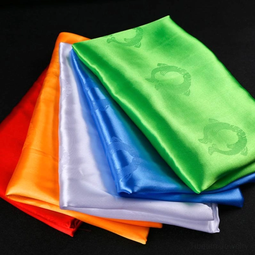 Tibetan khata scarves stacked showing smooth satin texture and embossed auspicious Buddhist symbols in five color options