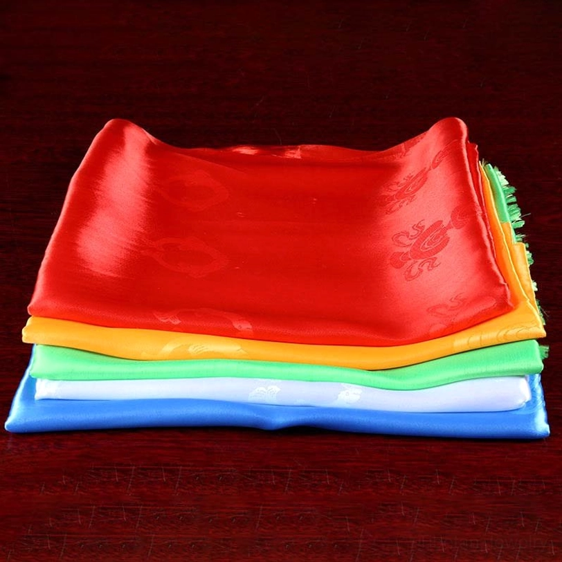 Neatly stacked Tibetan khata ceremonial scarves from top view showing all five colors and delicate embossed patterns