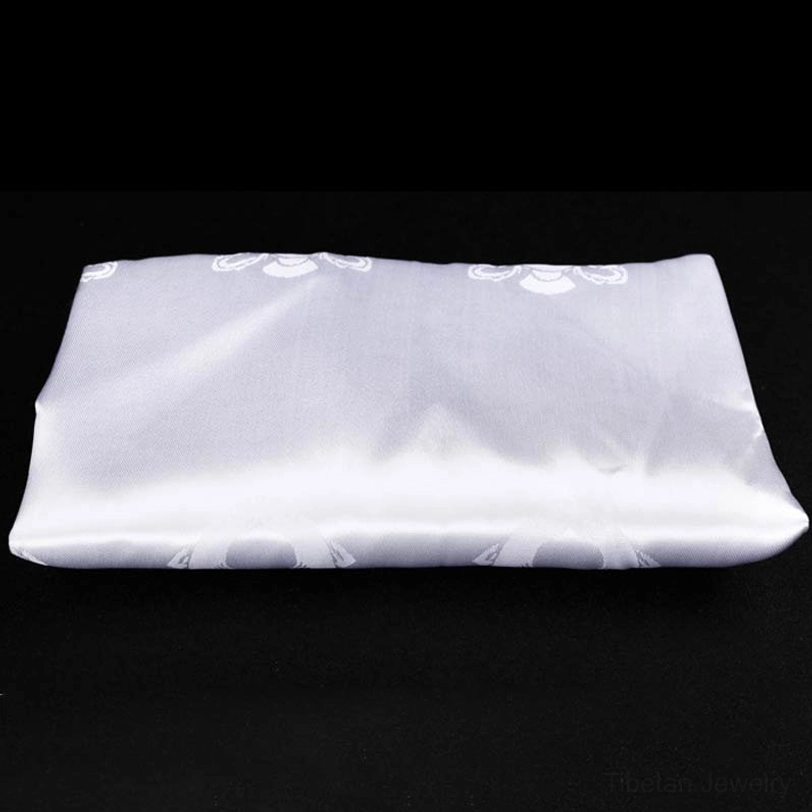 Single white Tibetan khata scarf with subtle embossed auspicious patterns on black background