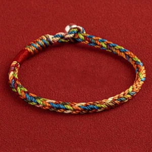 Tibetan King Kong knot multicolored woven bracelet with silver clasp, flat lay top-down view on red fabric background