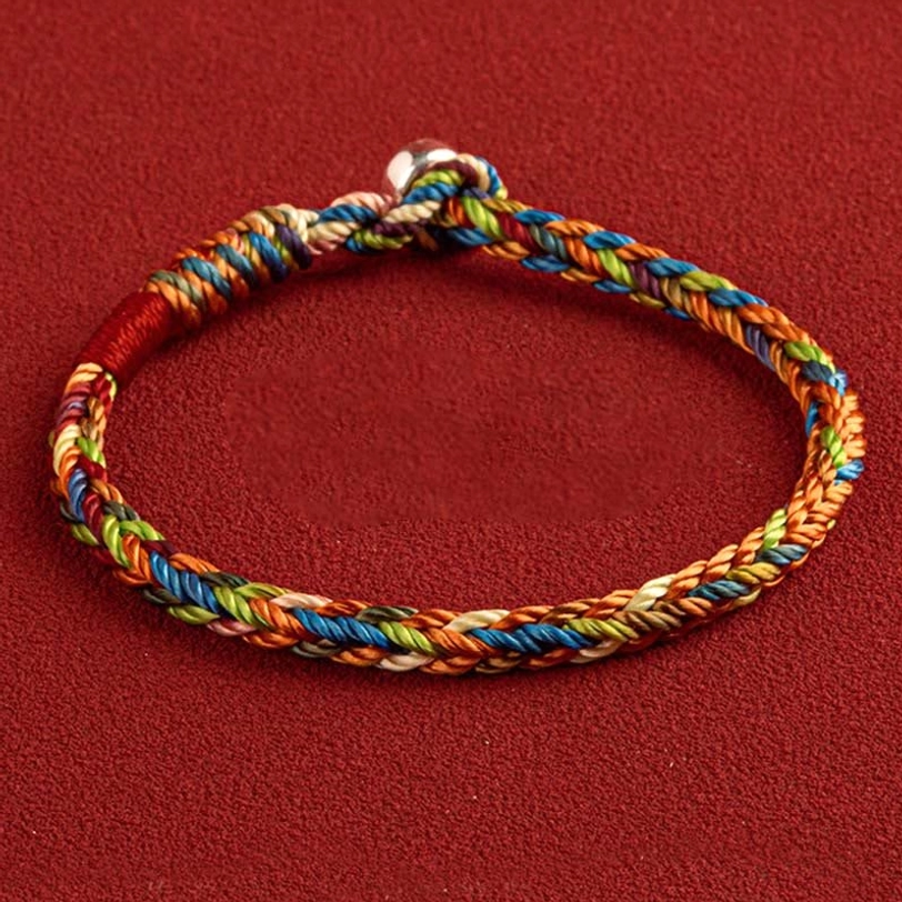Tibetan King Kong knot multicolored woven bracelet with silver clasp, flat lay top-down view on red fabric background