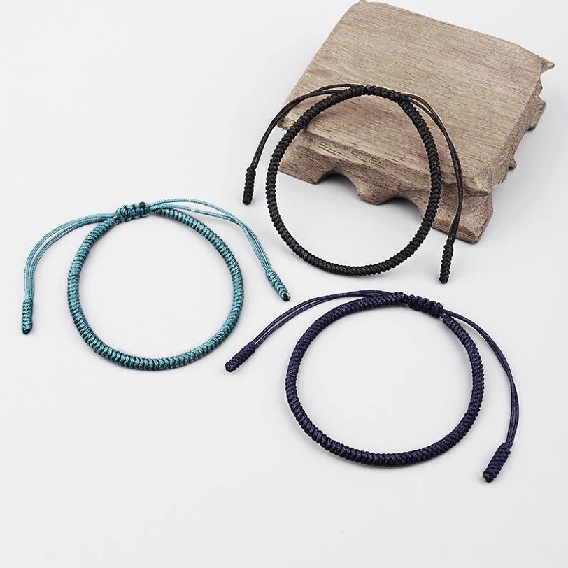 Tibetan protection bracelets displayed on wooden block showing adjustable cord ends and three color options