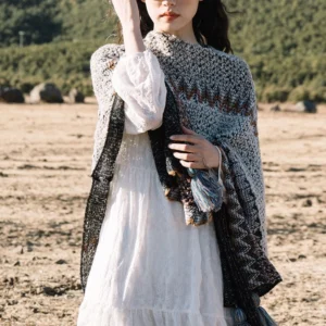 Front view of Tibetan knit poncho shawl featuring zigzag knit texture and dual-tone tassel trim with black side panels