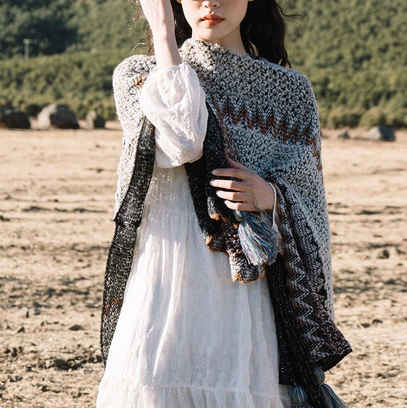 Front view of Tibetan knit poncho shawl featuring zigzag knit texture and dual-tone tassel trim with black side panels