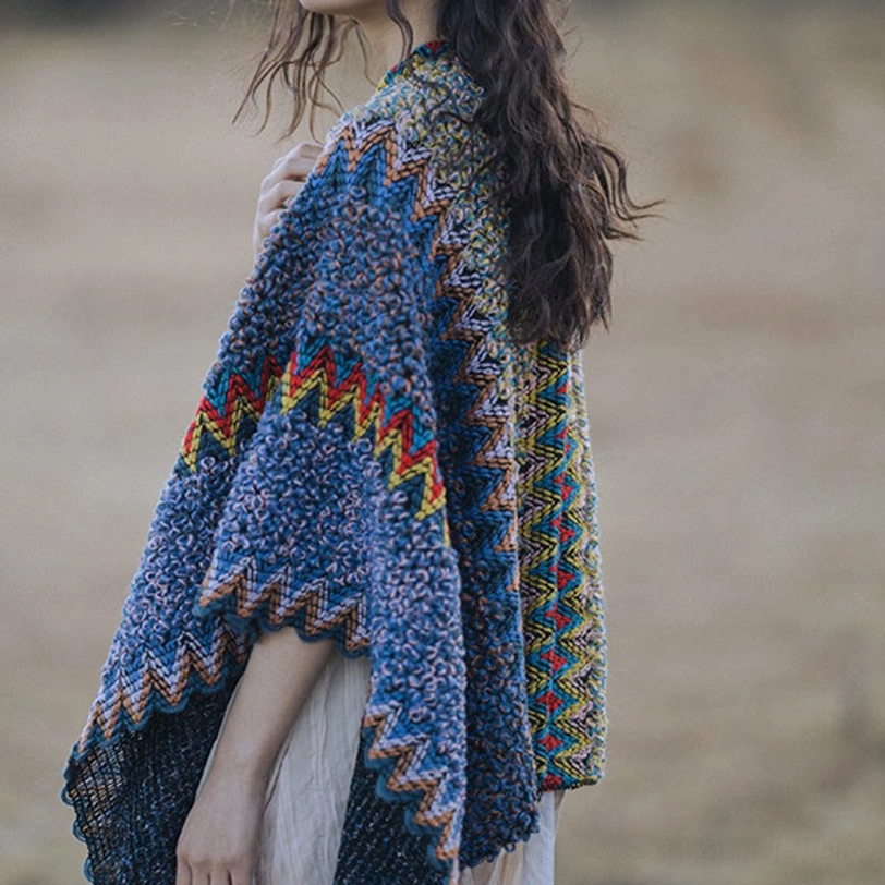 Side back three-quarter angle of Tibetan style knit poncho with zigzag ethnic pattern and draped loose fit