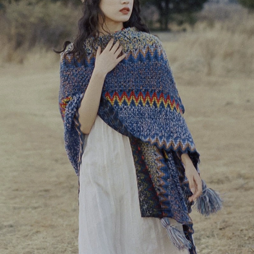Overhead flat lay of folded Tibetan knit shawl showing full chevron pattern and tassel trim arrangement