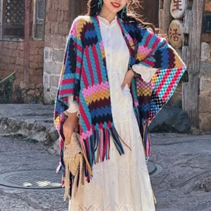 Colorful ethnic Tibetan knit shawl paired with white dress and straw bag in outdoor town square setting