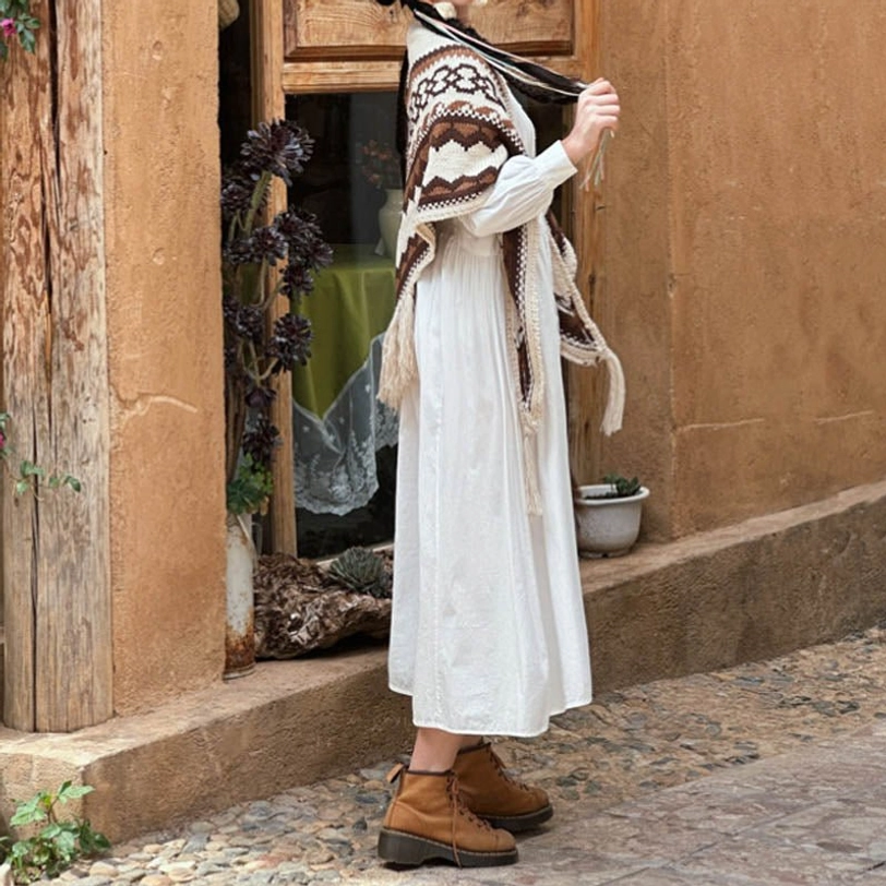Tibetan tassel shawl with brown beige geometric pattern draped on shoulders, rear partial view on cobblestone street