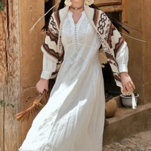 Boho tassel shawl draped over white lace dress, front partial view showcasing brown geometric pattern at rustic adobe entrance