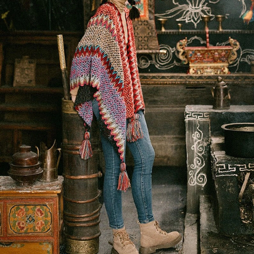 Ethnic Tibetan knitted poncho in red beige purple mixed tones with tassel trims and thick woven fabric, antique Tibetan room