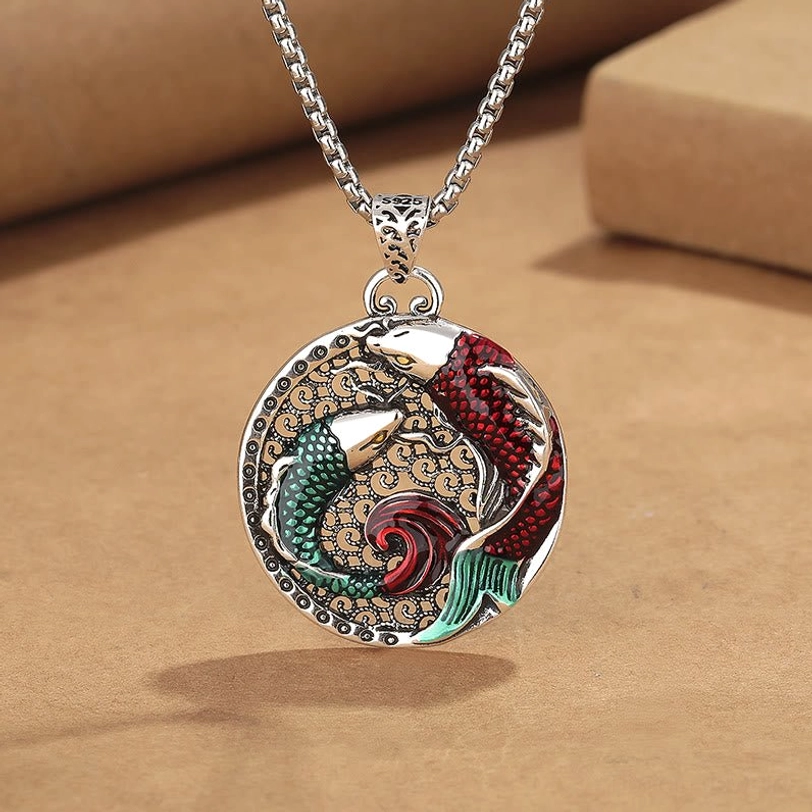 Tibetan copper koi fish pendant necklace with pearl chain, 45-degree close-up view showing detailed enamel red-green koi design on kraft paper background