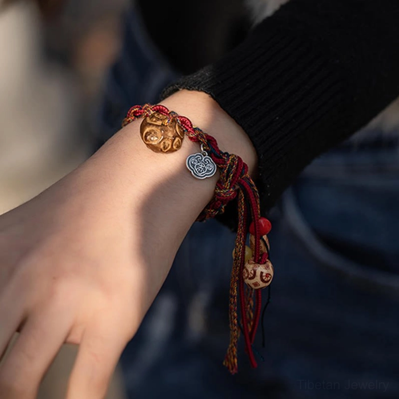 Koi fish silver charm and red braided cord bracelet worn on hand with casual sweater and denim
