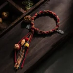 Handcrafted Tibetan koi fish red string bracelet with sterling silver charms and natural bodhi seed beads, displayed on dark wooden surface