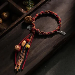 Handcrafted Tibetan koi fish red string bracelet with sterling silver charms and natural bodhi seed beads, displayed on dark wooden surface