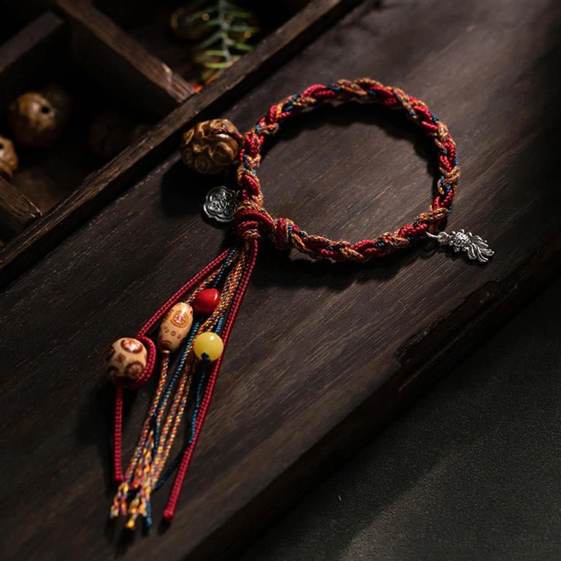 Handcrafted Tibetan koi fish red string bracelet with sterling silver charms and natural bodhi seed beads, displayed on dark wooden surface