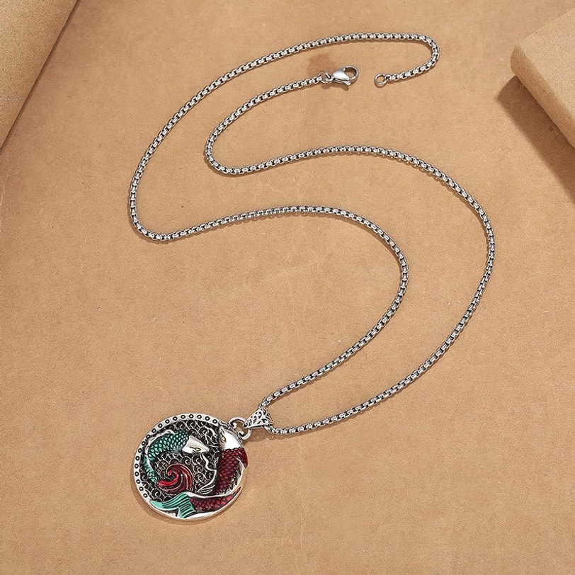 Handcrafted koi fish pendant necklace with wheat-link silver chain, overhead flat lay on kraft paper background