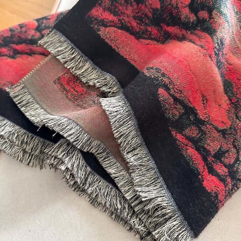 Detailed close-up of Tibetan scarf hem showing hand-knotted black tassels, frayed edge detailing, and soft woven textile construction