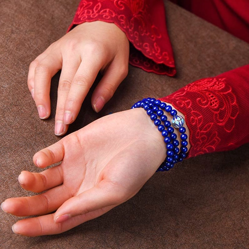 Single-wrap deep blue Lapis Lazuli healing bracelet with enamel decoration on resting hands
